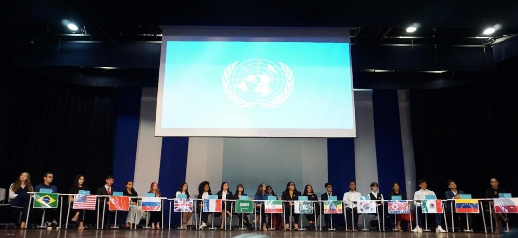 Estudantes do Ensino, sentados em fileira Médio representando os países na Simulação da ONU.