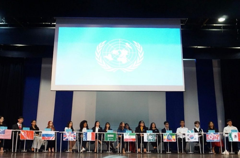 Estudantes do Ensino, sentados em fileira Médio representando os países na Simulação da ONU.